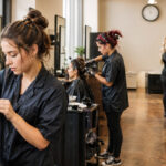 Cosmetology students progress from beginner hair sectioning to supervised client services and advanced hairstyling inside one realistic training classroom.
